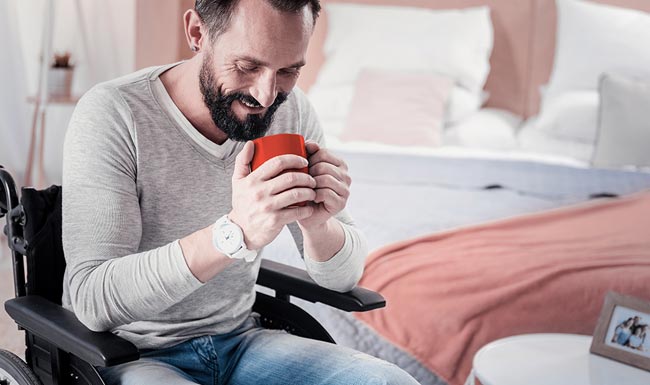 Person in wheelchair with traumatic brain injury enjoying coffee at home